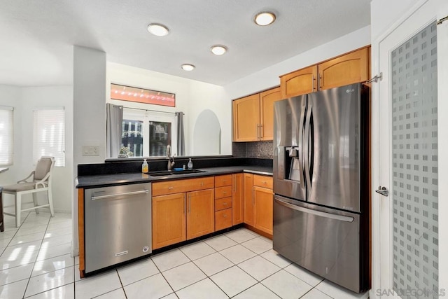 kitchen with appliances with stainless steel finishes, sink, decorative backsplash, and light tile patterned floors