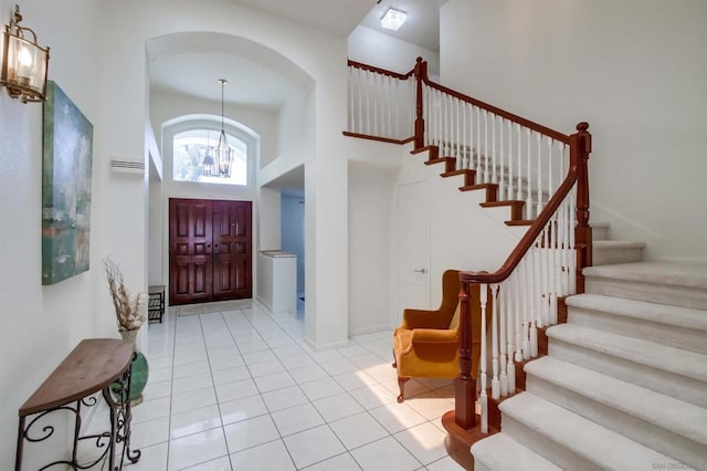 tiled entrance foyer with a towering ceiling and a chandelier