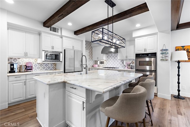 kitchen featuring white cabinetry, sink, stainless steel appliances, and an island with sink