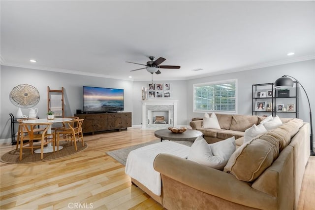 living room with light wood-style flooring, a fireplace, and crown molding