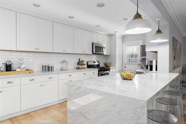 3140 Sumatra Pl, Costa Mesa, CA 92626 - kitchen with appliances with stainless steel finishes, decorative backsplash, light stone countertops, white cabinets, and light wood-type flooring