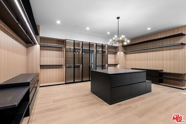 spacious closet with an inviting chandelier and light wood-type flooring