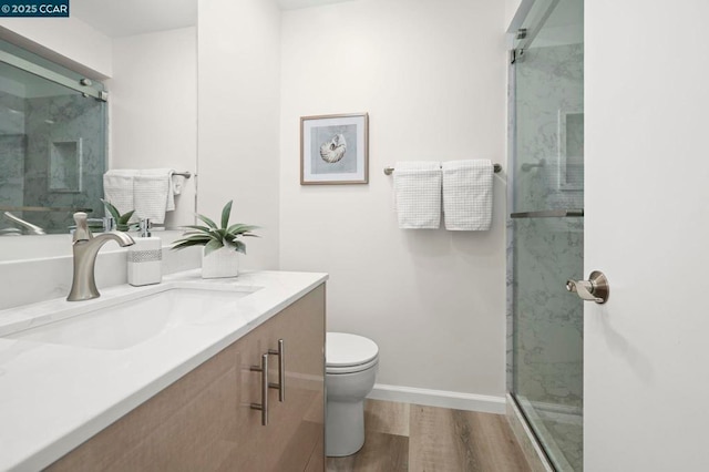 bathroom with vanity, hardwood / wood-style floors, a shower with door, and toilet