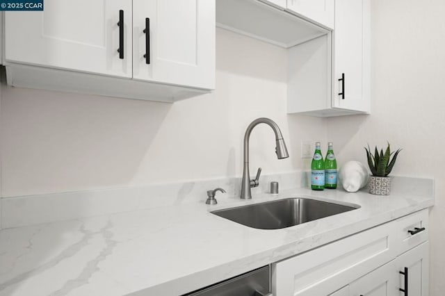 kitchen featuring light stone countertops, sink, and white cabinets