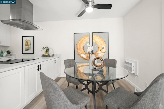 dining space featuring ceiling fan, a wall mounted AC, and light hardwood / wood-style flooring