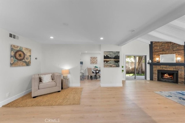 unfurnished room featuring a fireplace, lofted ceiling with beams, and light wood-type flooring