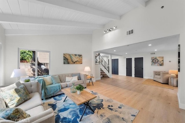 living room featuring vaulted ceiling with beams and light hardwood / wood-style flooring