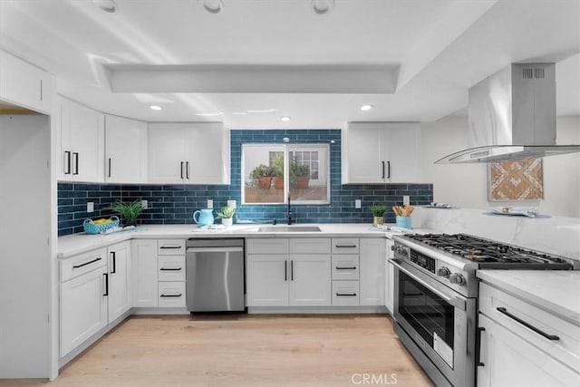 kitchen with stainless steel appliances, island exhaust hood, sink, and white cabinetry