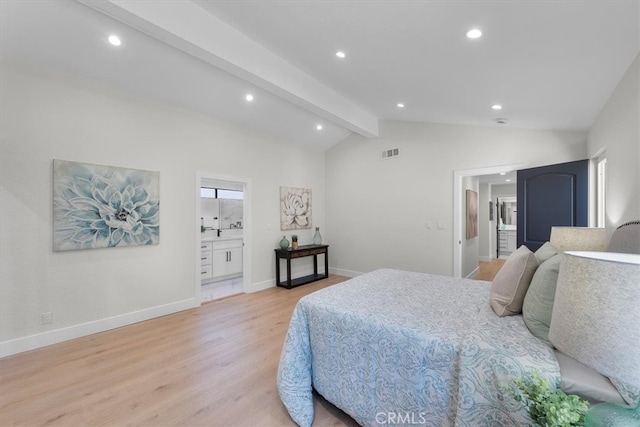 bedroom with lofted ceiling with beams, connected bathroom, and light hardwood / wood-style flooring