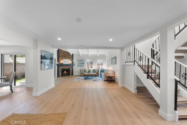 unfurnished living room with a stone fireplace, vaulted ceiling with beams, and light wood-type flooring