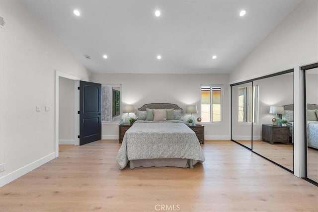 bedroom featuring two closets, light hardwood / wood-style flooring, and high vaulted ceiling