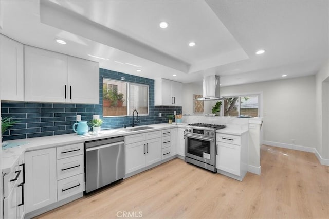 kitchen with appliances with stainless steel finishes, sink, island range hood, and white cabinets