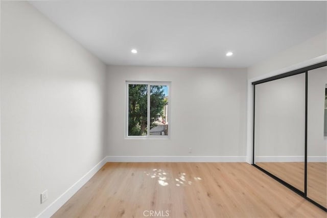 unfurnished bedroom with light wood-type flooring and a closet