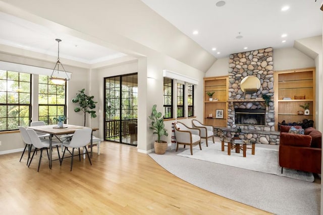 dining space featuring lofted ceiling, a fireplace, and light hardwood / wood-style flooring