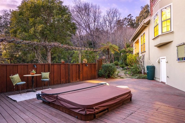 deck at dusk featuring a covered hot tub