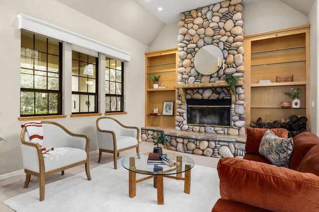 sitting room featuring lofted ceiling, light colored carpet, and a stone fireplace