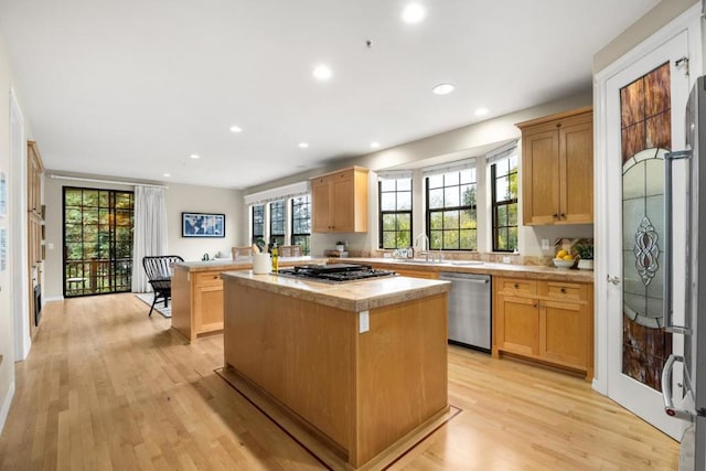 kitchen featuring stainless steel appliances, a kitchen island, and light wood-type flooring