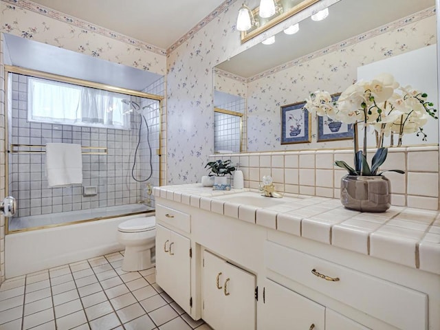 full bathroom with bath / shower combo with glass door, vanity, tile patterned floors, and toilet