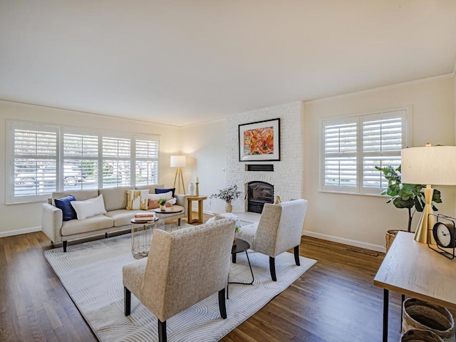 living room with ornamental molding, a brick fireplace, and dark hardwood / wood-style floors