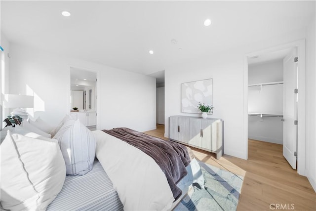 bedroom featuring a spacious closet, light hardwood / wood-style flooring, and a closet