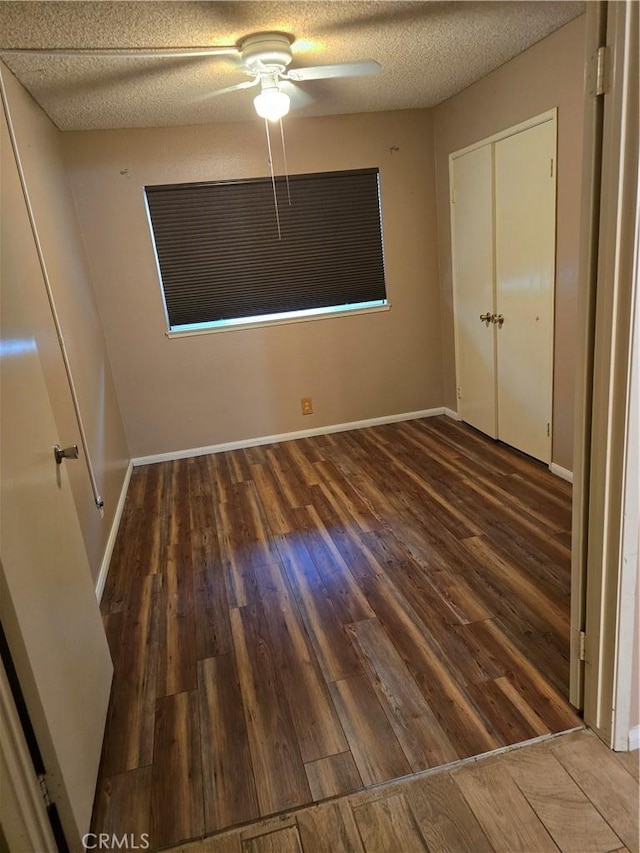 unfurnished bedroom featuring ceiling fan, a textured ceiling, and dark hardwood / wood-style flooring