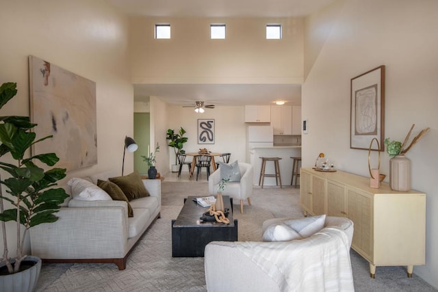 carpeted living room featuring a towering ceiling and ceiling fan