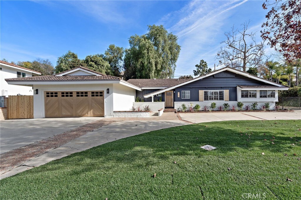ranch-style house with driveway, a garage, fence, and a front yard