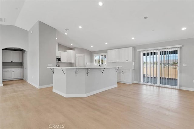 kitchen with white cabinetry, light countertops, light wood-style flooring, and a kitchen breakfast bar
