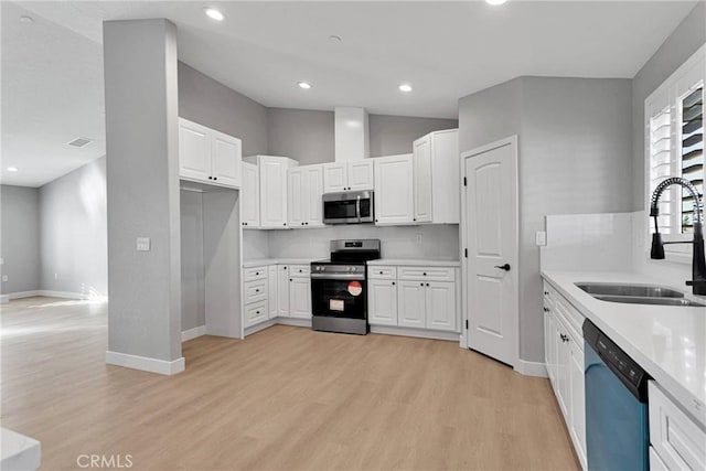 kitchen with white cabinets, visible vents, light wood-style flooring, appliances with stainless steel finishes, and a sink