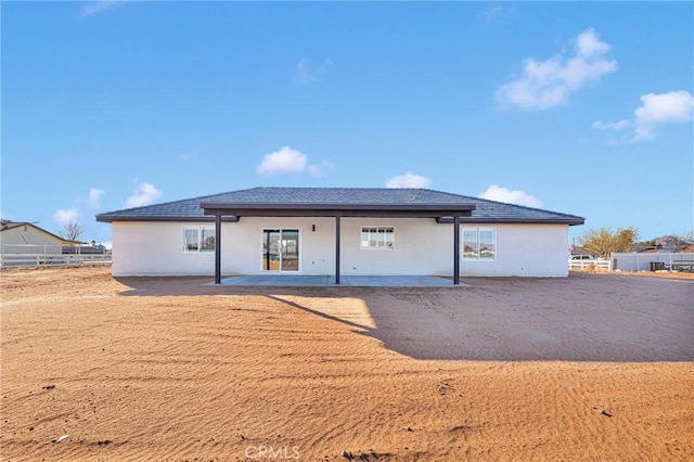back of property with stucco siding, fence, and a patio area