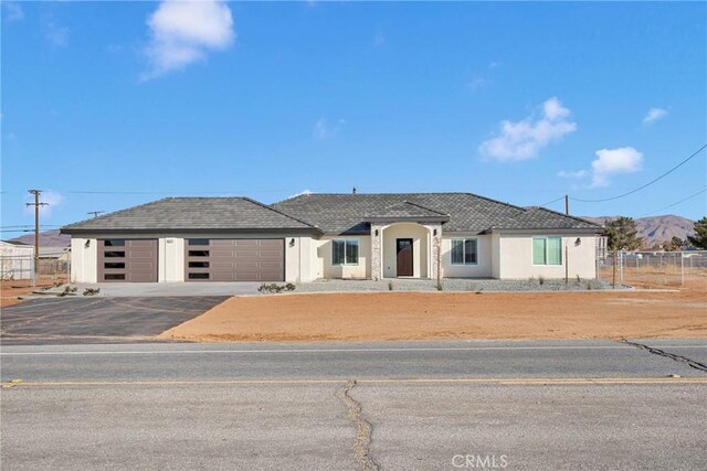 view of front of house with driveway, stucco siding, fence, and an attached garage