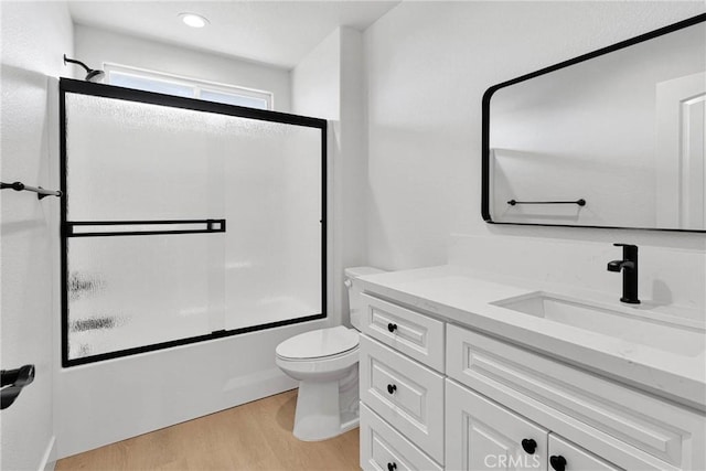 bathroom with toilet, shower / bath combination with glass door, wood finished floors, and vanity