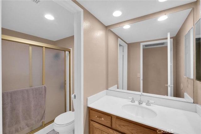 bathroom with vanity, a shower with shower door, and toilet