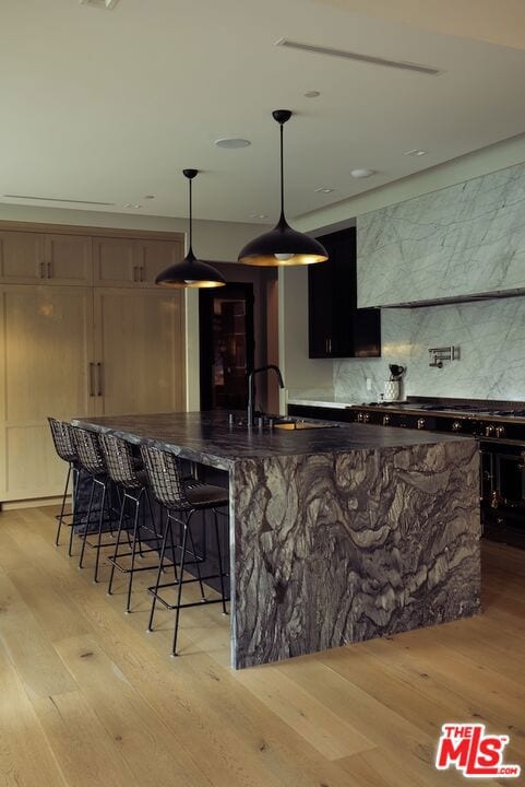 kitchen featuring pendant lighting, sink, a breakfast bar area, and light wood-type flooring