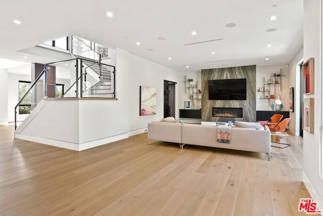 living room featuring a high end fireplace and light hardwood / wood-style flooring