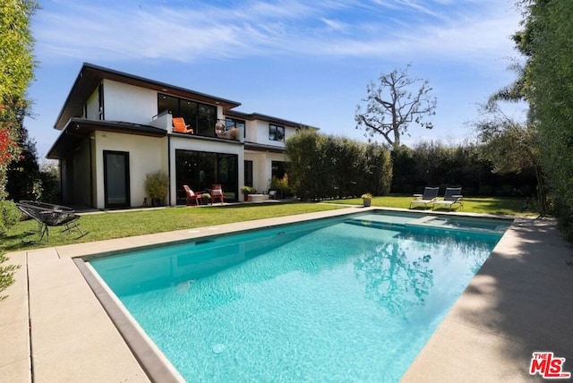 rear view of house featuring a balcony and a yard