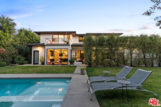 rear view of house featuring a yard, a patio, and a balcony