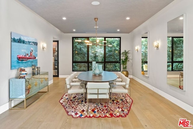 dining space featuring a healthy amount of sunlight, a notable chandelier, and light hardwood / wood-style floors