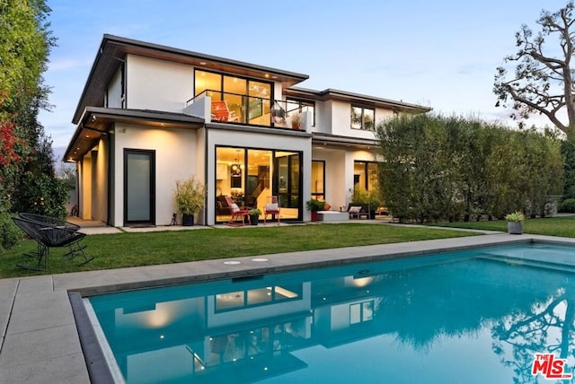 rear view of property featuring a yard and a balcony