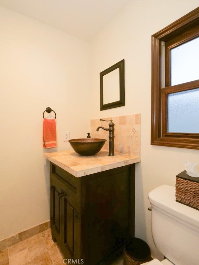 bathroom featuring vanity, toilet, and decorative backsplash