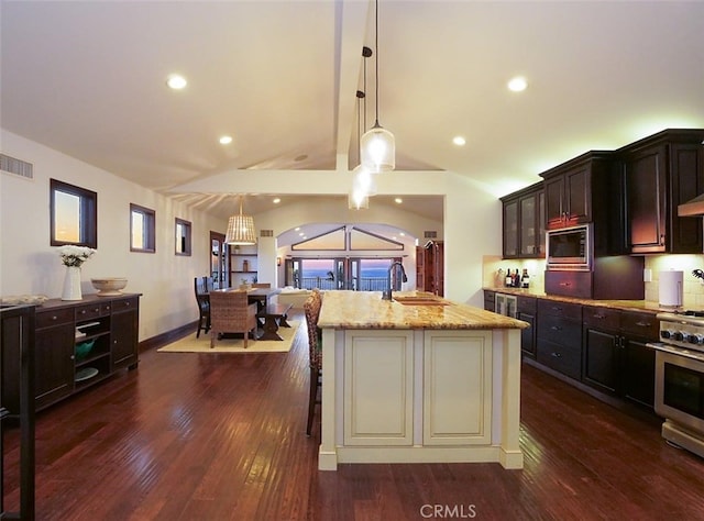 kitchen featuring an island with sink, lofted ceiling, sink, hanging light fixtures, and stainless steel appliances