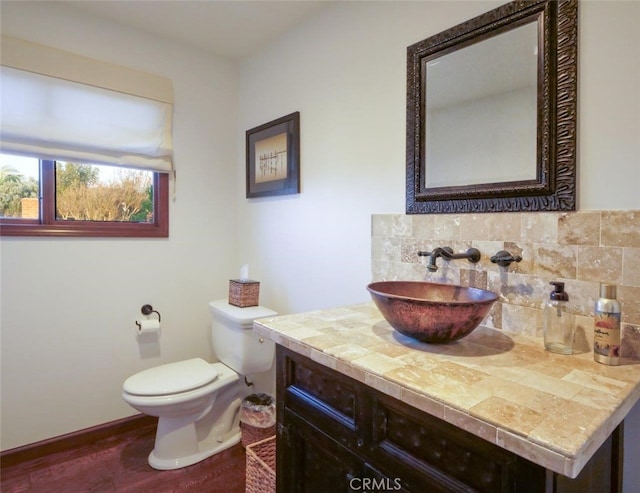 bathroom featuring toilet, wood-type flooring, vanity, and decorative backsplash