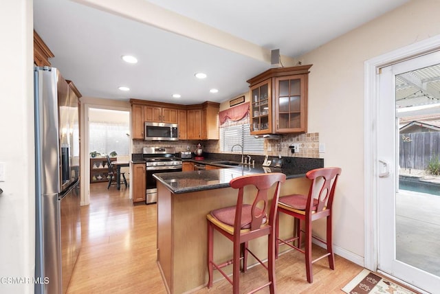 kitchen with backsplash, stainless steel appliances, kitchen peninsula, and a kitchen bar