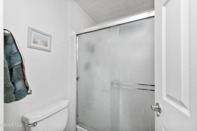 bathroom with a shower with door and toilet