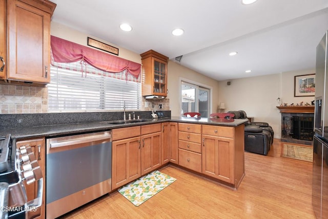 kitchen with sink, light wood-type flooring, kitchen peninsula, stainless steel appliances, and backsplash