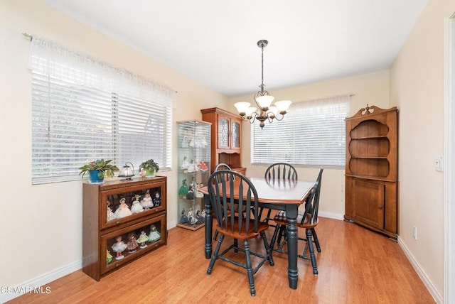 dining room with light hardwood / wood-style flooring, plenty of natural light, and an inviting chandelier