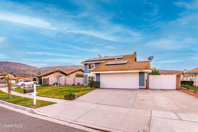 view of front of house featuring a mountain view, a front yard, and solar panels