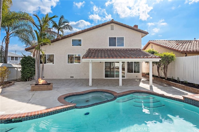 rear view of property featuring an outdoor fire pit, a pool with hot tub, and a patio