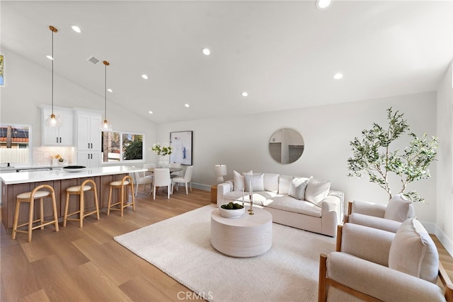 living room with high vaulted ceiling and light hardwood / wood-style flooring