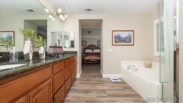 bathroom featuring vanity, tiled tub, hardwood / wood-style flooring, and a notable chandelier